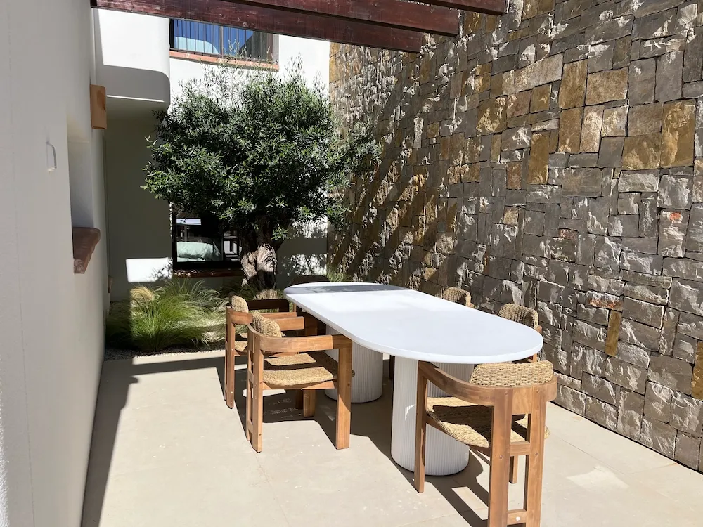 Table and chairs on a terrace with a olive tree behind